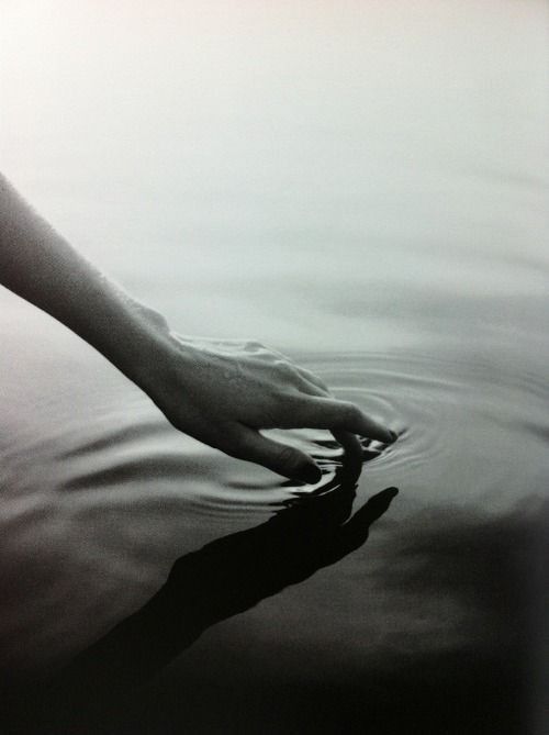 a person's hand reaching for something in the water