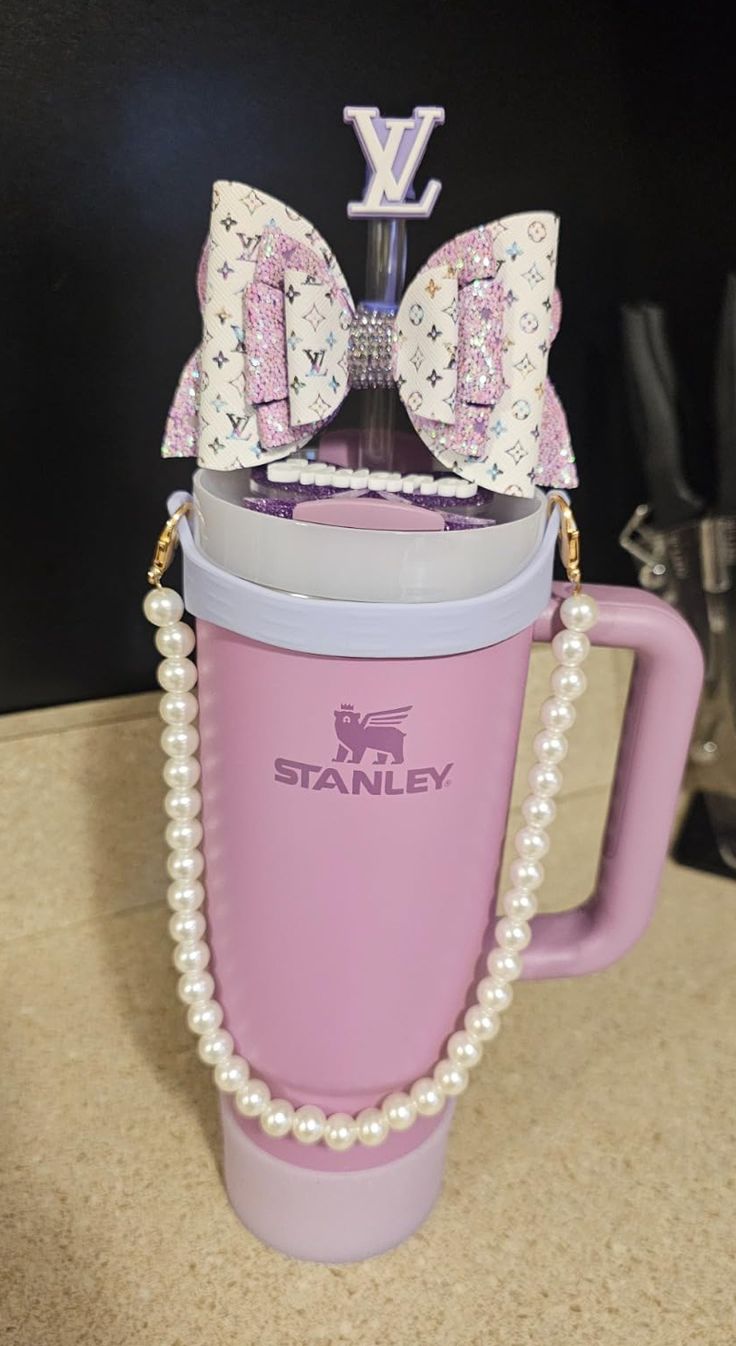 a pink coffee cup with a bow and pearls on the handle is sitting on a counter