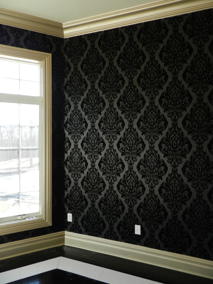 an empty room with black and white wallpaper in the corner, next to a window