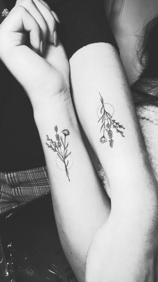 two people with matching tattoos on their arms, one is holding the other's arm