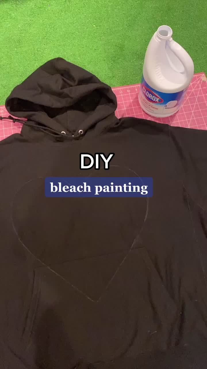 a black hoodie sitting on top of a table next to a bottle of paint