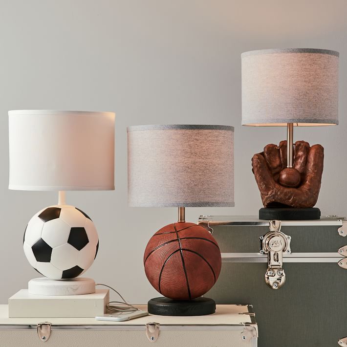 three lamps with different types of sports balls on top of each other and one lamp has a hand holding a soccer ball