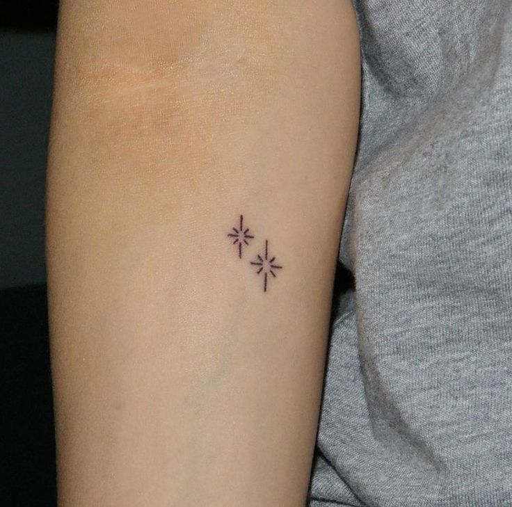 a small cross tattoo on the arm