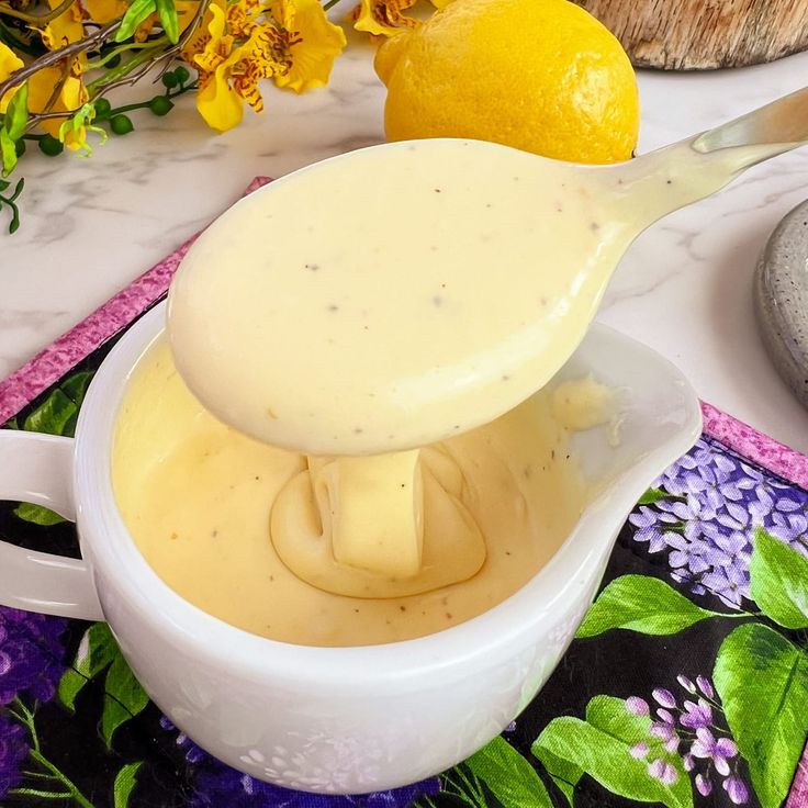 a spoon is pouring liquid into a bowl with lemons on the table next to it