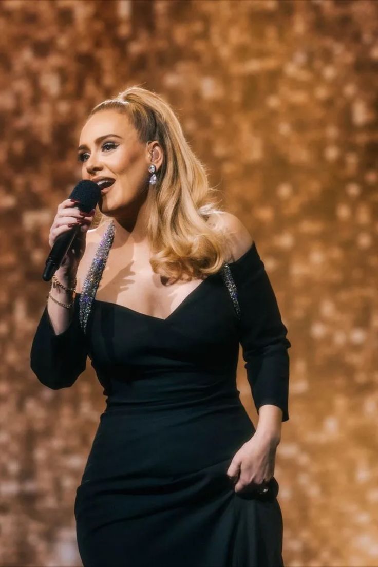 a woman in a black dress holding a microphone