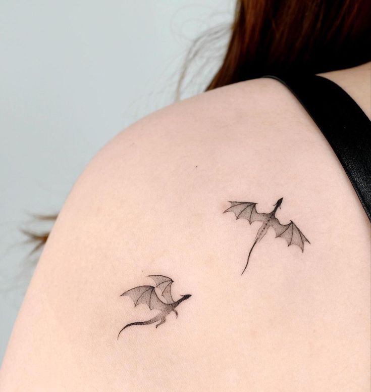 a woman's shoulder with two flying bats on it