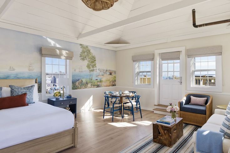 a bedroom with white walls and wood floors, blue furniture and paintings on the wall