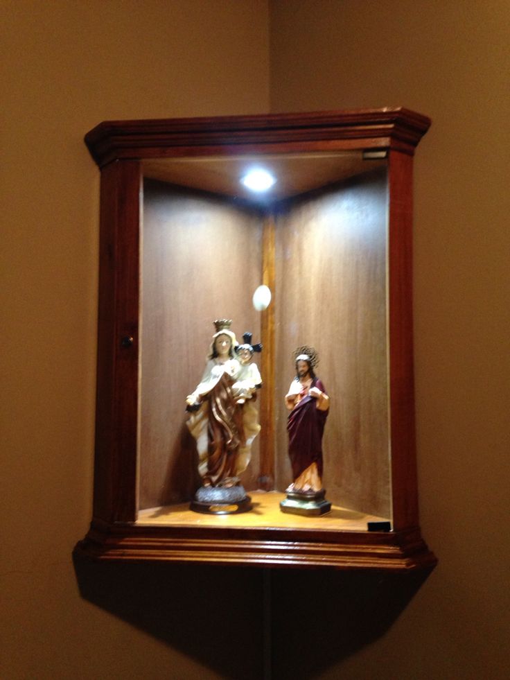 two figurines in a wooden case on top of a shelf next to a light