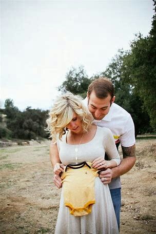 a man and woman standing next to each other holding a baby in a yellow dress