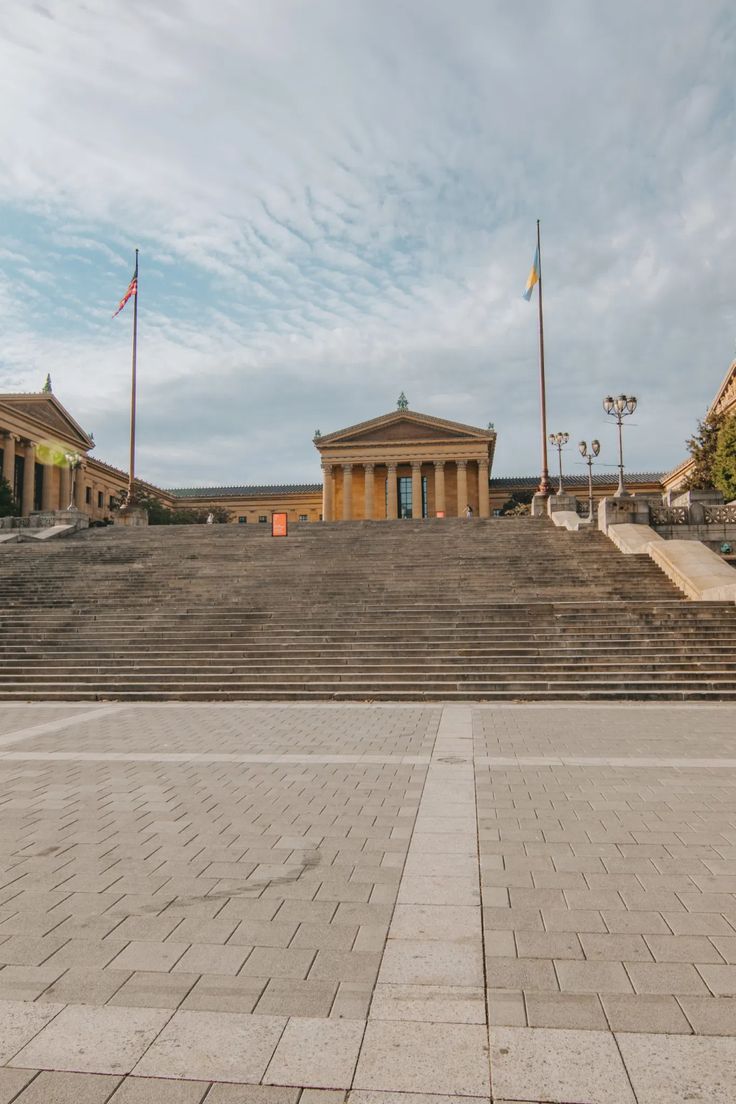 an empty building with steps leading up to it and two flags flying in the air