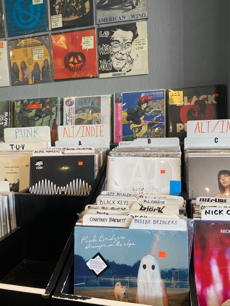 many records are stacked on top of each other in front of a wall full of pictures