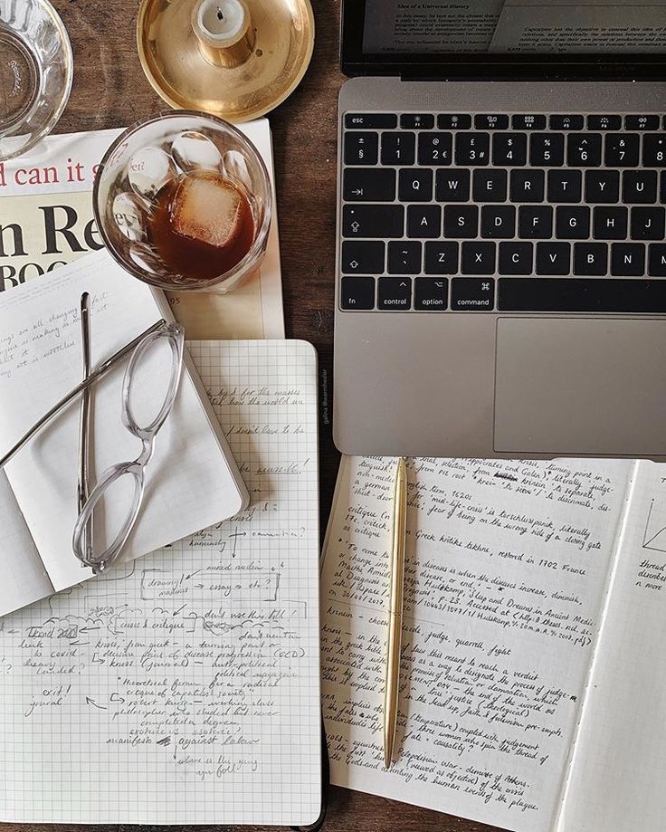 an open notebook with glasses on top of it next to a laptop and coffee cup