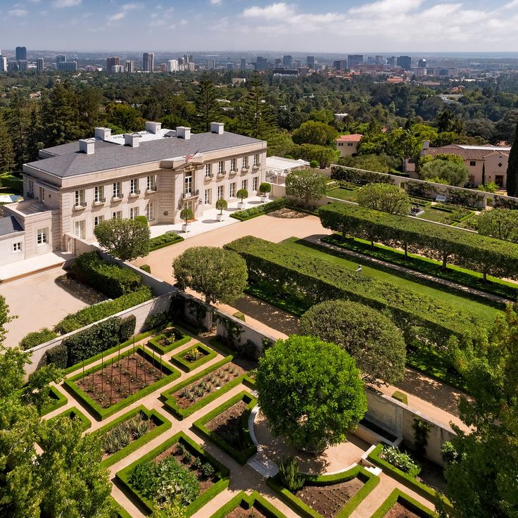 an aerial view of a large house surrounded by trees and hedges in the foreground