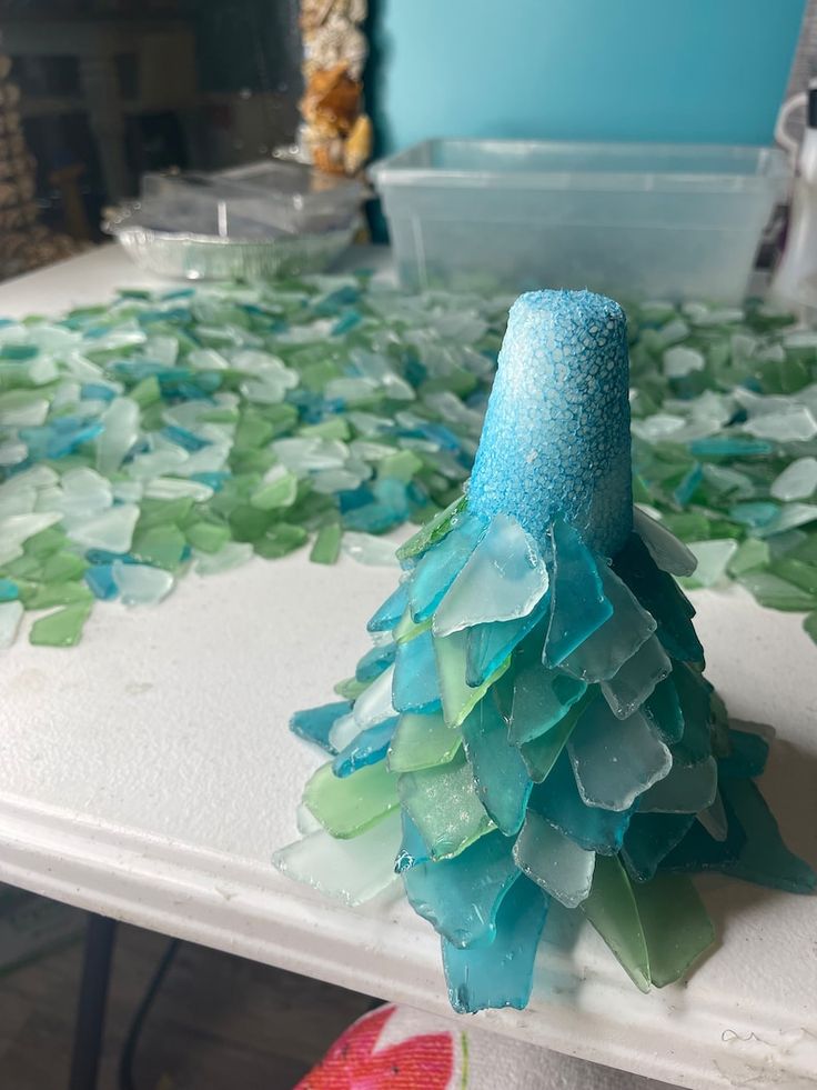 a blue and green tree made out of sea glass on top of a white table