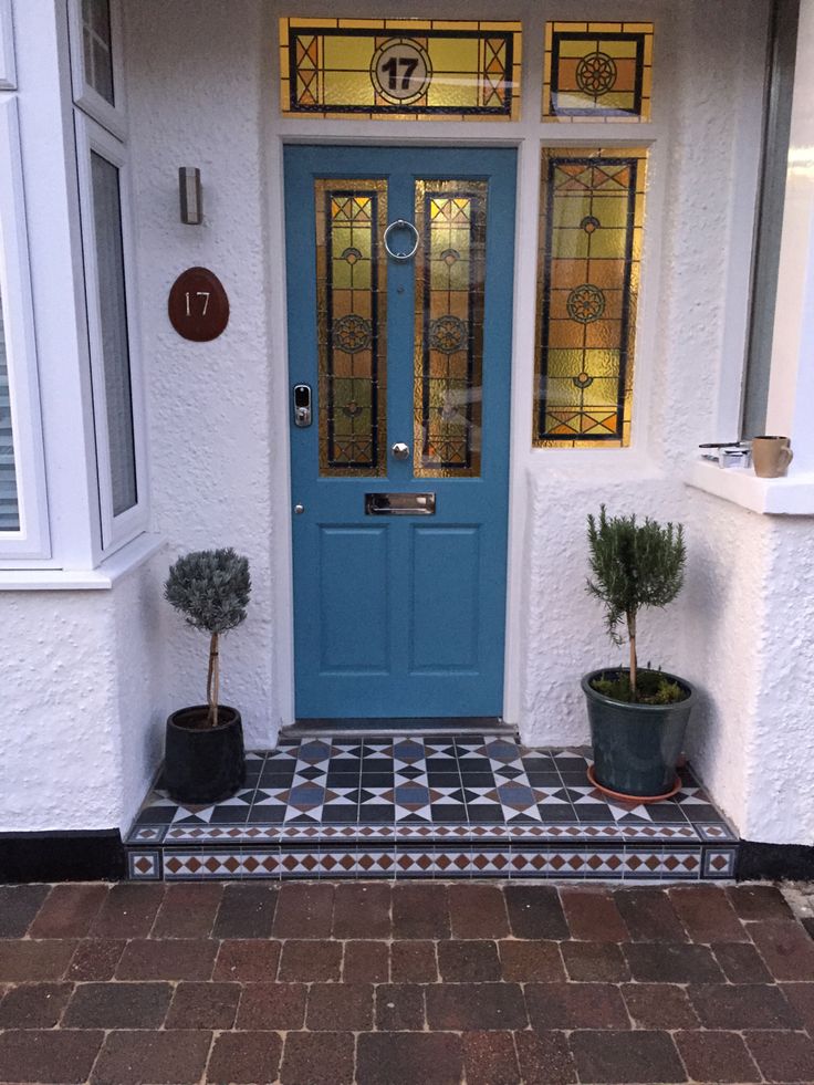 a blue front door with two potted plants