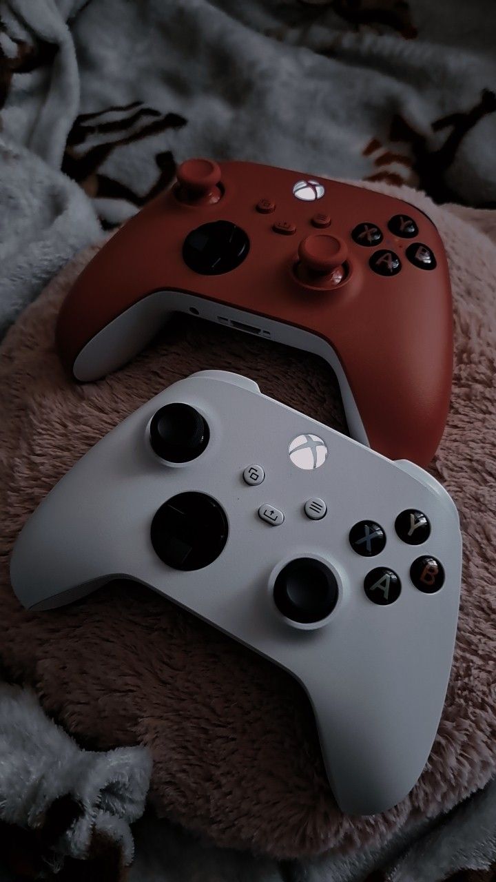 two video game controllers sitting on top of a blanket