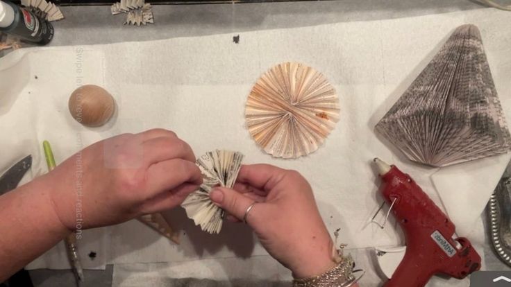 a woman is working on some shells with scissors and threading needles, along with other craft supplies