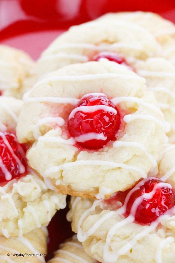 cookies with white icing and cherries are on a red plate