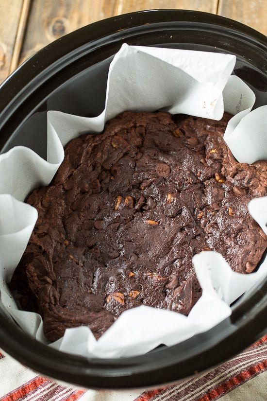 a close up of a chocolate cake in a crock pot on a wooden table