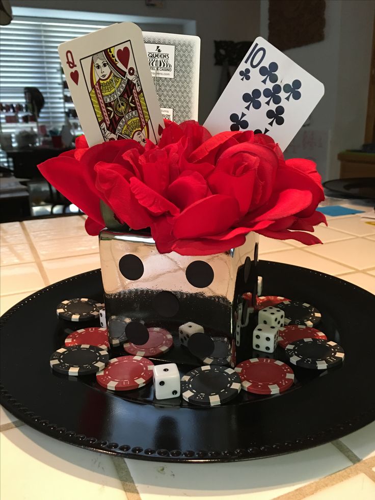 a black plate topped with cards, dices and a red rose sitting on top of it