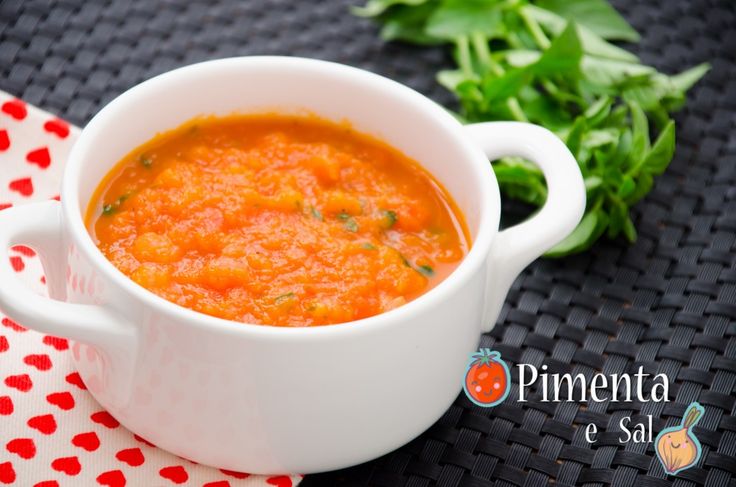 a white bowl filled with soup next to some parsley on a red and white napkin