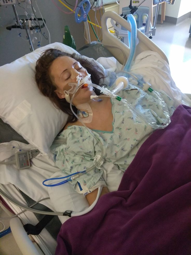 a woman laying in a hospital bed with an oxygen tube attached to her head and breathing apparatus