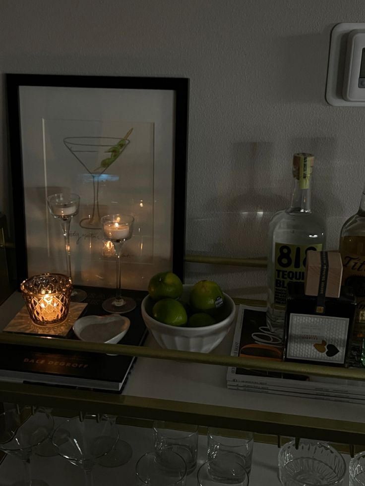 a shelf filled with bottles and glasses on top of a counter next to a candle