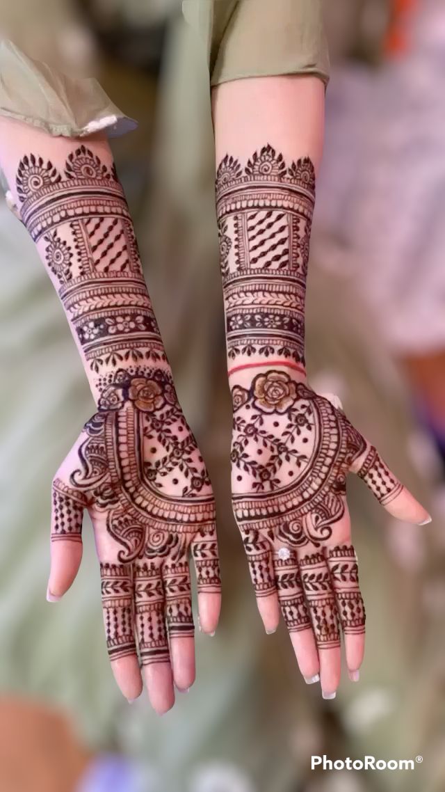 two hands with henna tattoos on their palms and arms, both decorated with intricate designs