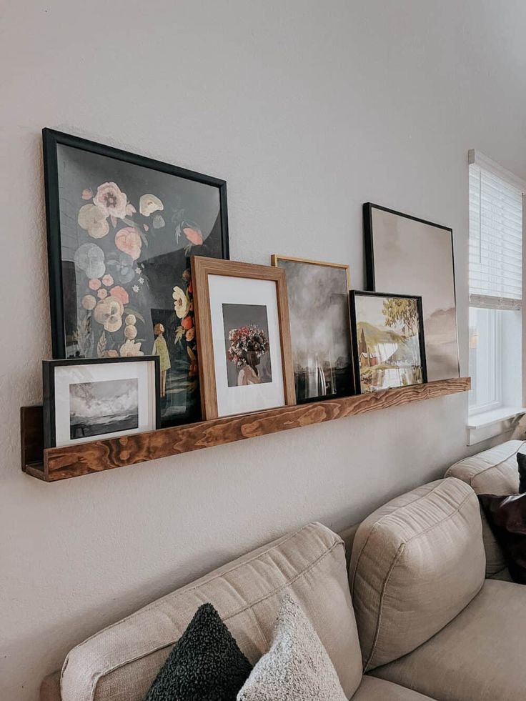 a living room filled with furniture and framed pictures on the wall above it's couch