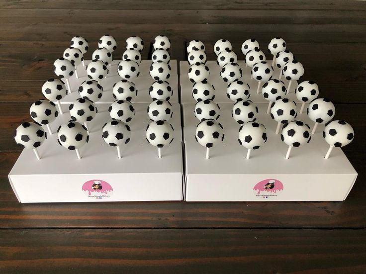 two white boxes with black and white soccer balls on top of each box are lined up in rows