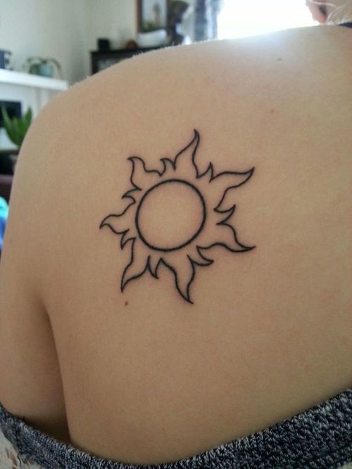 a sun tattoo on the back of a woman's shoulder