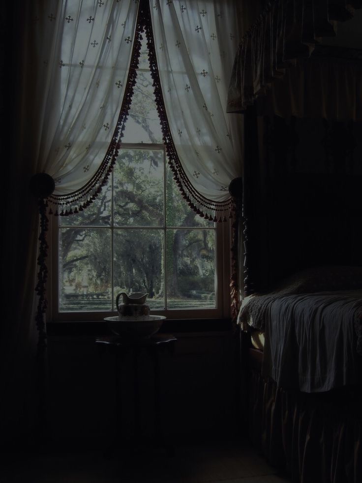 a bed sitting next to a window in a dark room