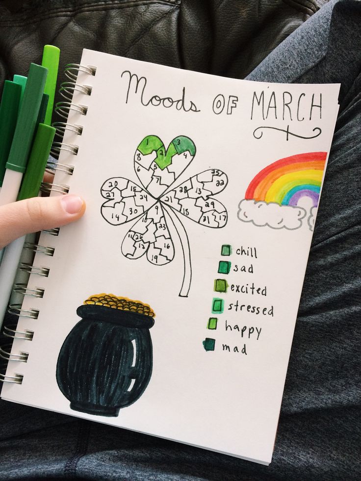 a hand holding a notebook with an image of a pot of gold and shamrocks on it