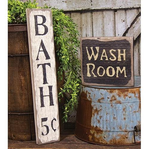 a bath room sign sitting on top of a wooden barrel next to a planter