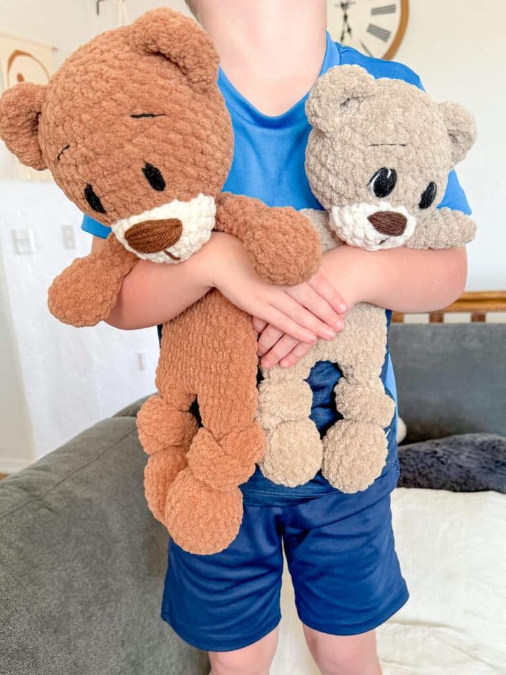 a little boy holding two teddy bears in his arms