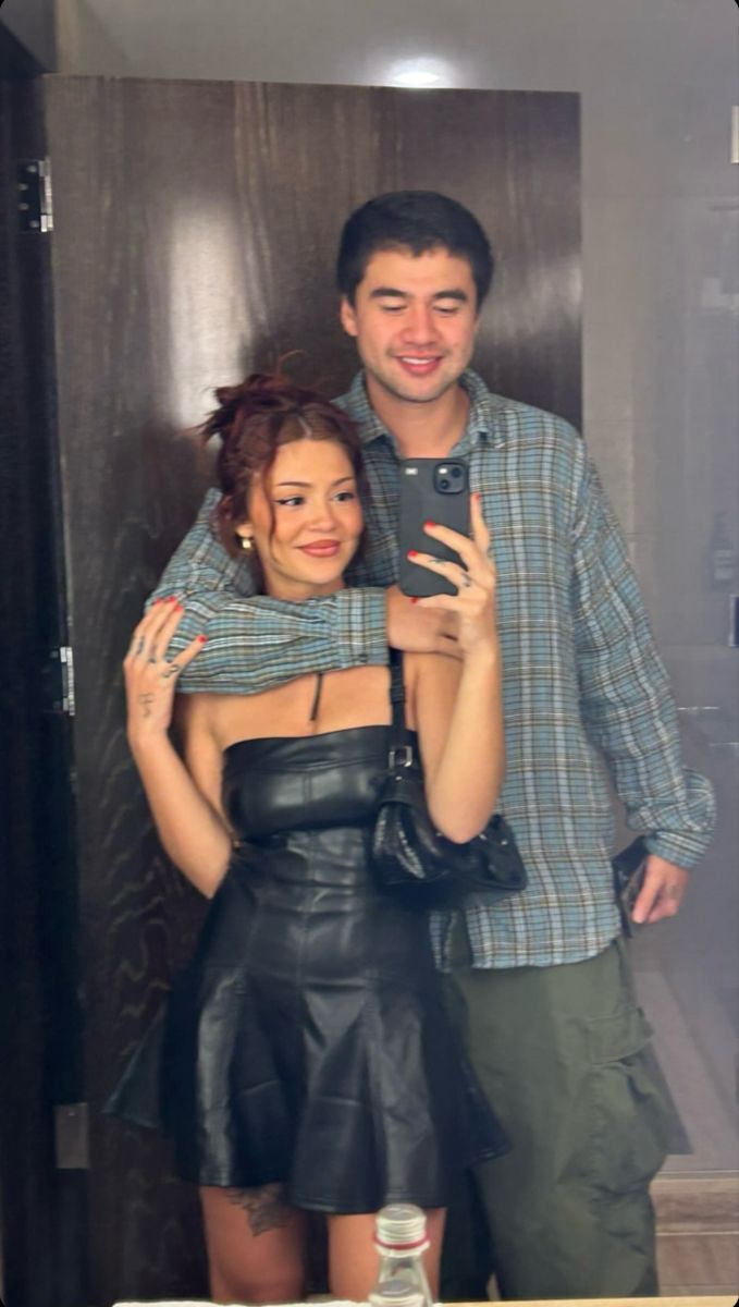 a man and woman taking a selfie in front of a mirror with their arms around each other