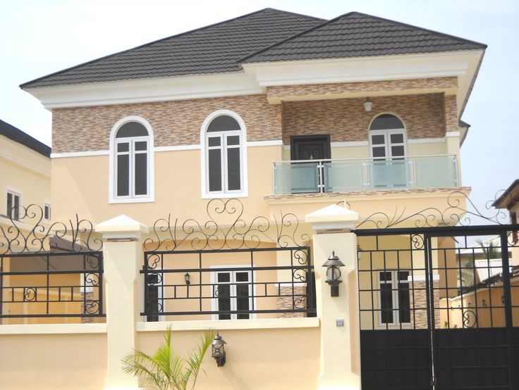 a house that is painted yellow and has black iron railings on the front door