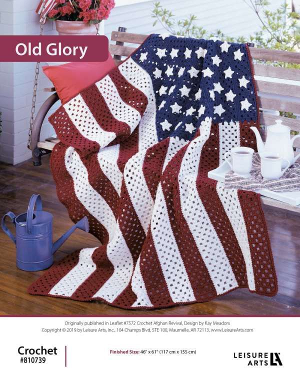 an american flag quilt on a porch with potted flowers and watering can in the background