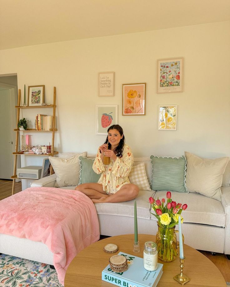 a woman sitting on top of a couch in a living room next to a coffee table