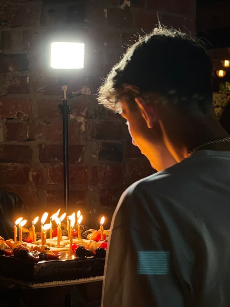 a man standing in front of a cake with lit candles