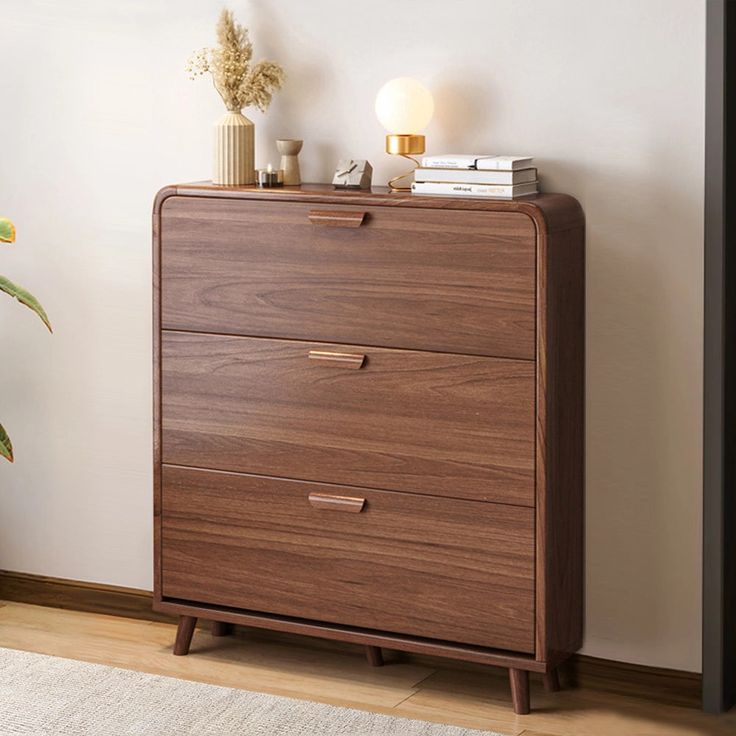 a wooden dresser sitting next to a plant in a living room on top of a hard wood floor