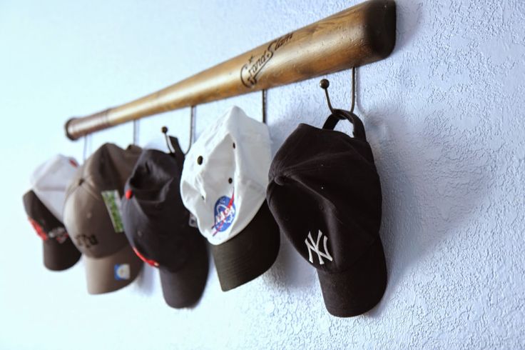 a baseball bat and several hats hanging on a wall