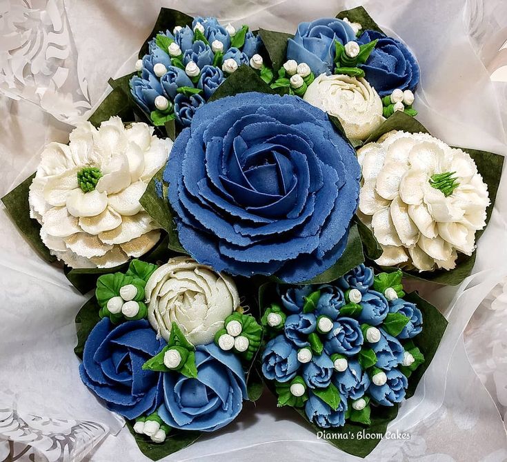 a bouquet of blue and white flowers sitting on top of a cloth covered tablecloth