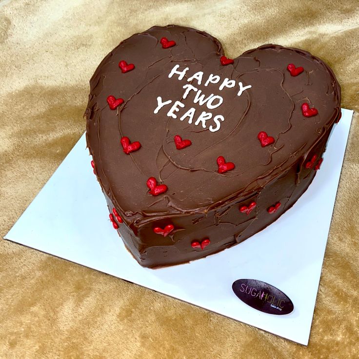 a heart shaped chocolate cake on top of a white paper with the words happy two years written on it