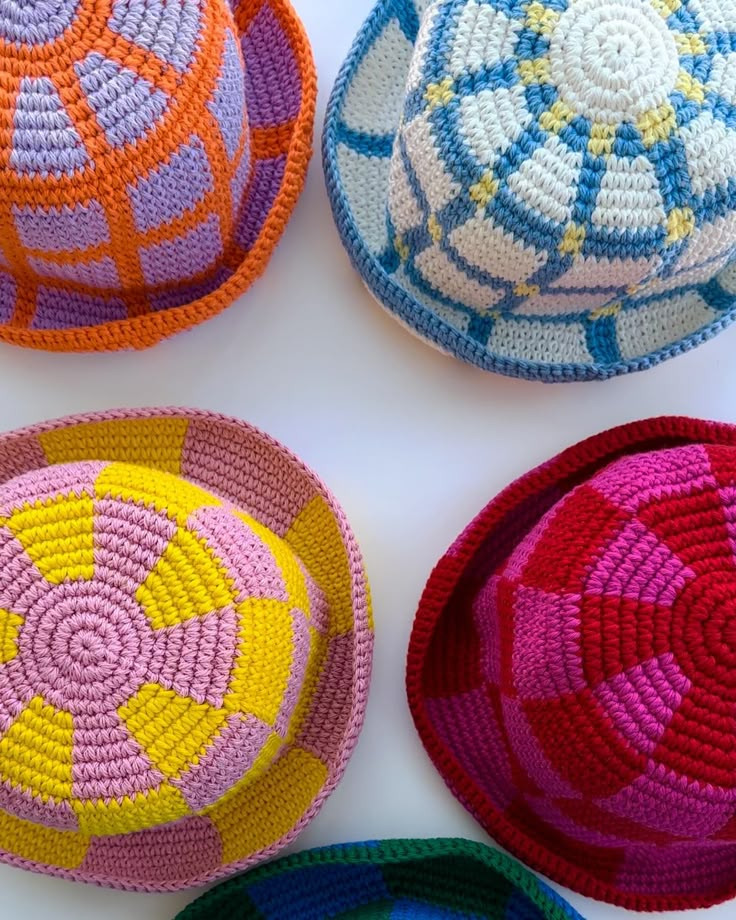 four crocheted baskets sitting on top of a white table