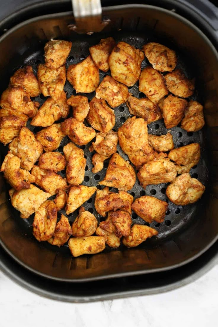 chicken is cooking in an air fryer on the stove top, ready to be cooked