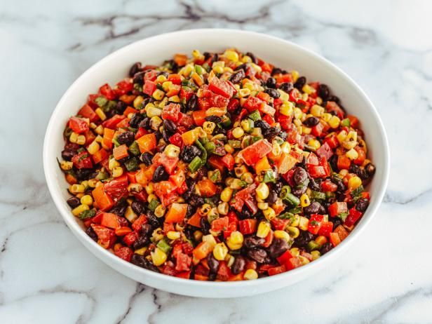 a white bowl filled with black beans, corn and peppers on top of a marble counter