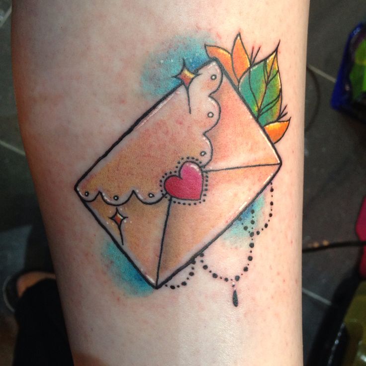 a small tattoo on the leg of a woman with an envelope and heart in it