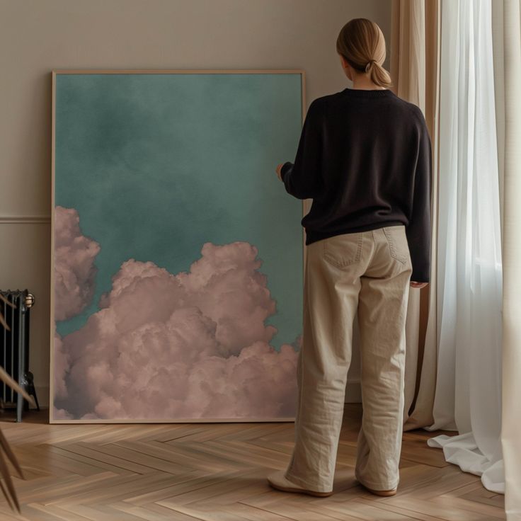 a woman standing in front of a painting on the wall looking at it's clouds