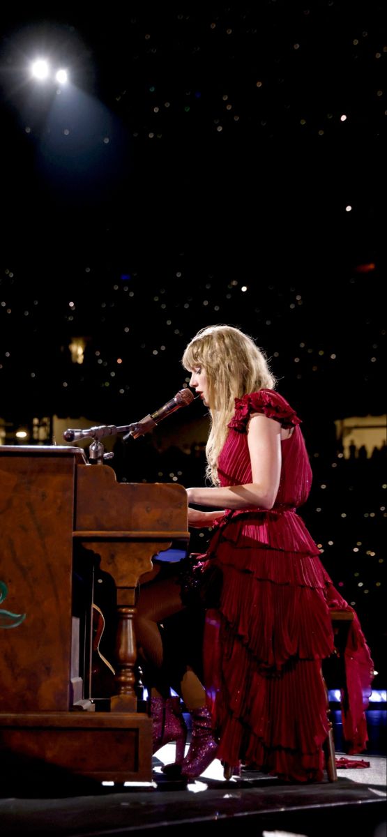 a woman in a red dress is playing the piano